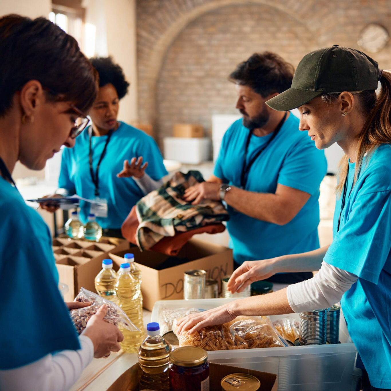 Diverse group of people sorting donated food for those in need while working at community center, Donations